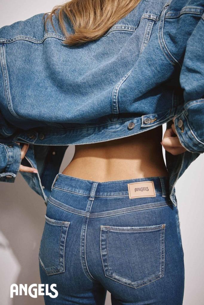 person, die eine blaue jeansjacke und blaue jeans trägt, mit dem rücken zur kamera. die jeans hat einen beigen aufnäher mit der aufschrift angels. das wort angels erscheint in weißer schrift in der unteren linken ecke.